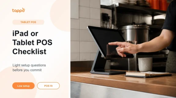 Tablet POS on a counter stand with an operator hand in a small restaurant